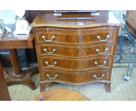 A good quality reproduction serpentine fronted chest of four drawers, of small proportions, having dressing slide, raised on 