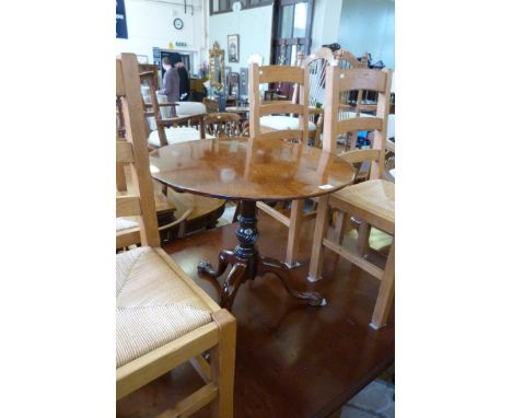 A Georgian mahogany circular topped tripod table raised on carved baluster supports terminating on ball and claw feet.