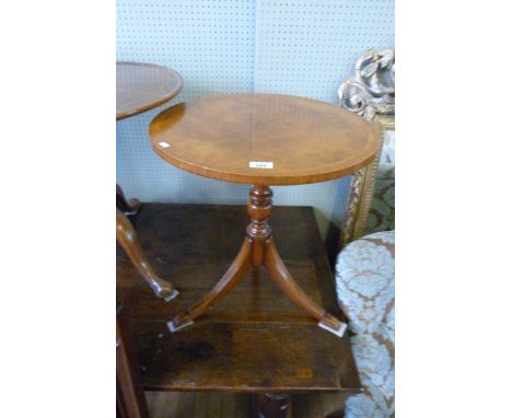 A reproduction burr walnut lamp table with circular top, raised on baluster form support.