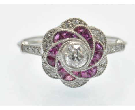 A platinum ruby and diamond ring. The ring set with a central round brilliant cut diamond and calibre ruby in a floral cluste