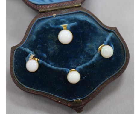 A cased early 20th century four piece yellow metal and white opal dress stud set.
