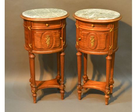 A Pair of French Oval Lamp Tables, each with a variegated marble top above a frieze drawer and cupboard door, raised upon tur