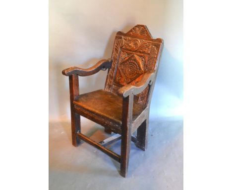An Early Oak Wainscott Armchair with a carved panel back above a panel seat raised upon square legs with stretchers 