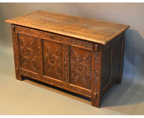 An Oak Coffer, the hinged top above a carved three panel front flanked by stiles, 108 cms wide x 51 cms deep x 64 cms high 