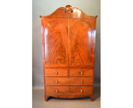 A William IV Mahogany Press Cupboard, the shaped moulded cornice above two arched doors enclosing sliding trays, the lower se