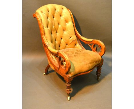 A Victorian Mahogany Button Leather Upholstered Library Armchair with turned tapering legs, brass caps and ceramic castors 
