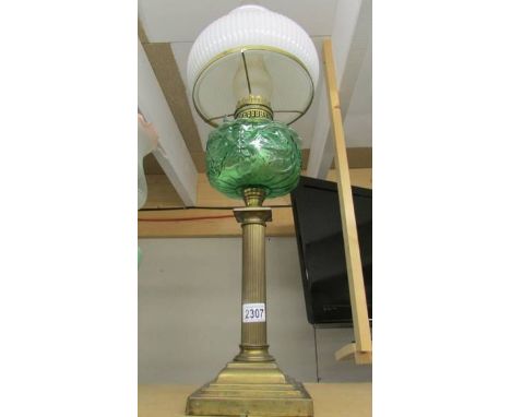 A brass oil lamp with green glass shade.