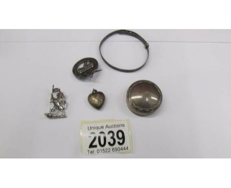 A silver bangle, a silver brooch, a silver badge, a silver locket and a silver pill box.