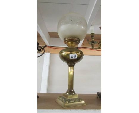 A brass oil lamp with etched shade.