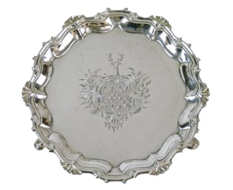 Small George II silver salver or visiting card tray having a pie-crust edge and standing on triple pad feet, engraved coat of