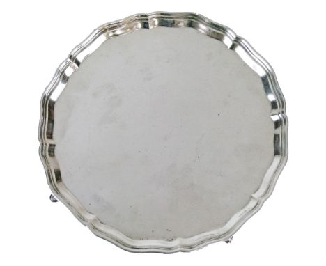 George V silver salver having a pie-crust edge and standing on four pad feet, makers Thomas Bradbury & Sons Ltd, Sheffield 19