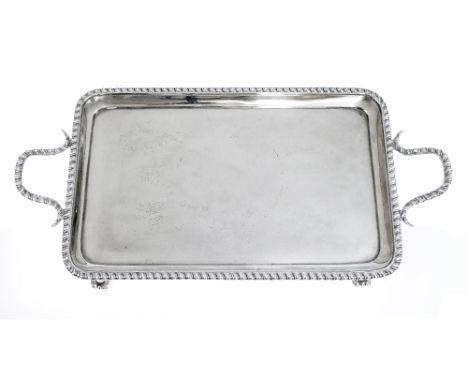 Victorian silver rectangular two handled tray, both the edge and the handles with gadrooned decoration and standing on scroll
