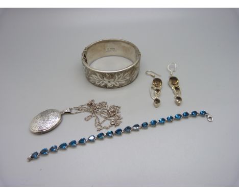 A silver bangle, a silver locket and chain, a pair of silver and smoky quartz earrings and a silver and blue stone set bracel