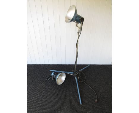 Two blue industrial lamps, one on tripod, the other on bracket 