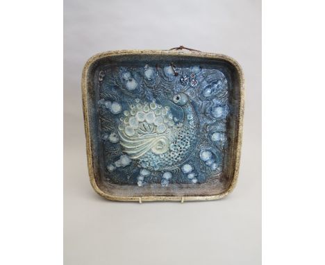 A rectangular ceramic platter with peacock relief, signed and dated 1980 to reverse, 29.5cm x 31cm 