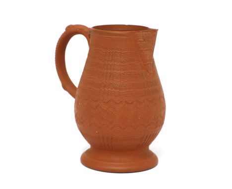 A Staffordshire redware baluster-shaped milk jug,c.1765, with a basket moulded loop handle and all-over engine-turned decorat