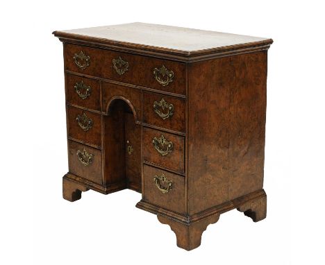 A Queen Anne burr elm kneehole desk, a quarter veneered top and fitted with one long and six small drawers to a small central