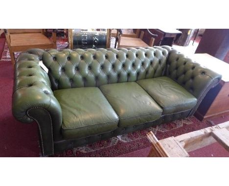 A three seater chesterfield sofa, with green leather button back upholstery, raised on castors 