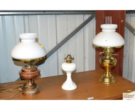 A brass oil lamp with opaque shade; another converted to electricity; and a small opaque glass oil lamp