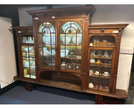 An Edwardian oak top section of a dresser with ornately carved paneling and glazed features, on unassociated oak church pew b