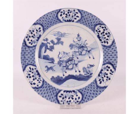 A blue/white porcelain dish, China, Kangxi style, 19th century. Blue underglaze decor of hunters in landscape, the lip with n