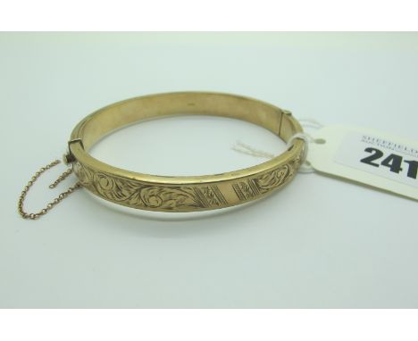 A 9ct Gold Hinged Bangle, leaf scroll engraved to the front, hinged to snap clasp (dents / safety chain broken) (10.5grams). 