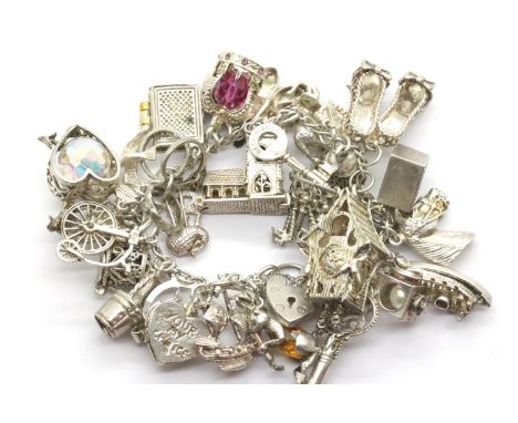 Heavy silver charm bracelet with more than twenty charms, 114g. P&P Group 1 (£14+VAT for the first lot and £1+VAT for subsequ