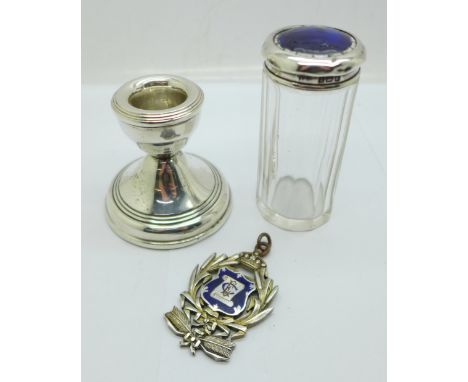 A silver candlestick, a large silver and enamel lodge medal, loop repaired, and a silver topped glass bottle, lid a/f 