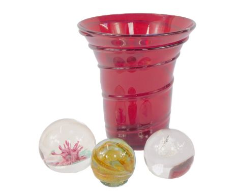 A Whitefriars ruby glass vase, with ribbon trailed decorations,19cm high, together with three glass paperweights. (4)