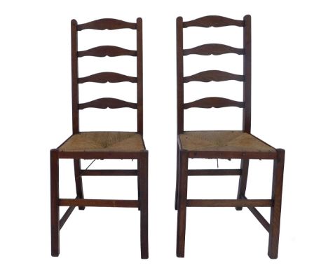 A pair of 19thC oak country made ladder back chairs, each with a rush seat, on square legs united by stretchers.