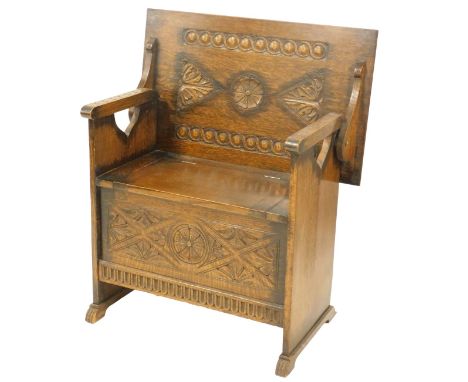 A 20thC oak monk's bench, with a carved floral top, hinged seat with a carved front, on paw feet, 68cm high when folded down,