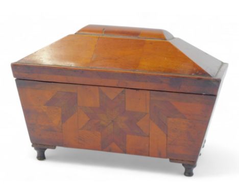 A Regency mahogany and parquetry sarcophagus shaped tea caddy, the front decorated with a star motif, the hinged lid enclosin