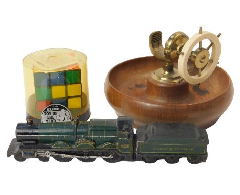 A wooden and brass ship's wheel nut cracker, 13cm high, together with a Rubik's Cube, and a cast iron model of a locomotive a