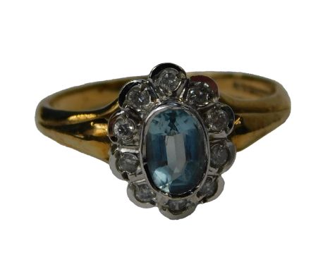 An 18ct gold aquamarine and diamond dress ring, the oval aquamarine in a rub over setting, surrounded by ten round brilliant 