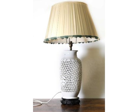 A Chinese blanc de chine ceramic table lamp, of balaster form, pierced with moulded prunus and bamboo decoration, on a carved