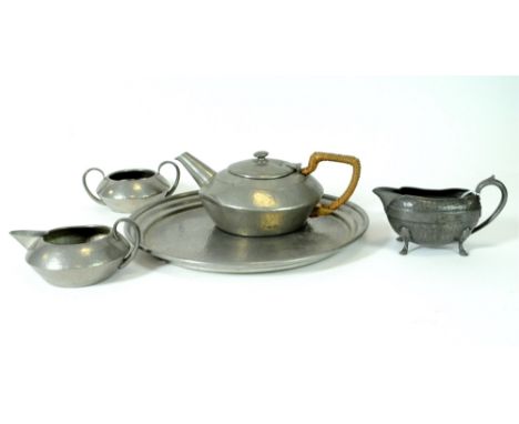 A three-piece Tudric hammered pewter tea-set comprising tray, teapot, milk jug and twin-handled sugar basin, together with a 