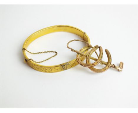 A 9ct gold hollow bangle, with bright cut decoration (at fault), together with a yellow metal double horseshoe brooch and a 9