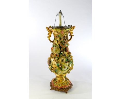 A large floral encrusted lamp base 19th century of twin-handled form and with polychrome relief flowers throughout, mounted o