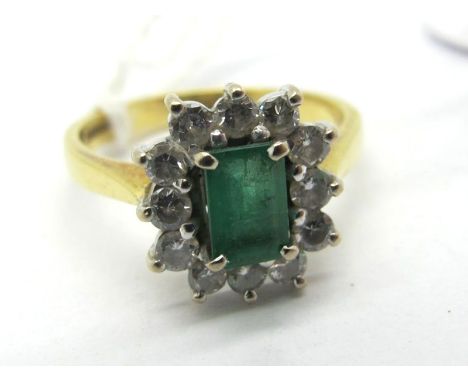 An 18ct Gold Emerald and Diamond Cluster Ring, rectangular four claw set to the centre, within border of brilliant cut diamon