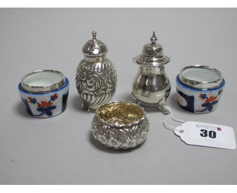 A Pair of Hallmarked Silver Mounted Ceramic Salts, (dents); Together with Two Hallmarked Silver Pepperettes, (one initialled)