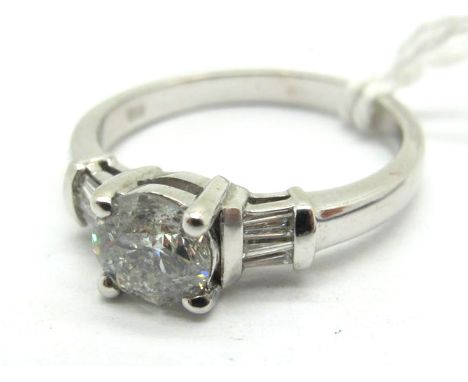 An 18ct White Gold Single Stone Diamond Ring, the (6mm) brilliant cut stone four claw set, between baguette cut diamond set s