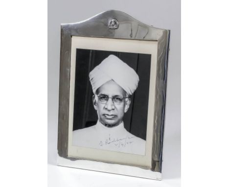 An Indian plain silvery metal rectangular photograph frame with arched top, with floral cast motif to arch and oak easel patt