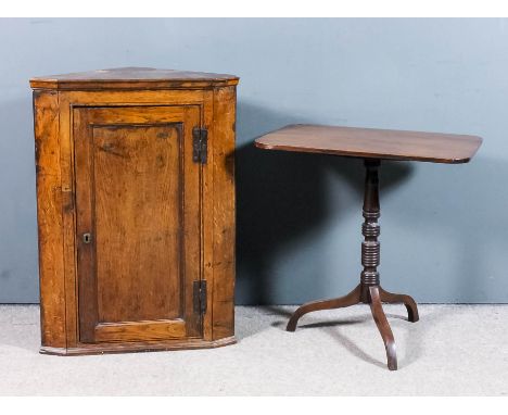 A small 18th Century oak hanging corner cupboard, fitted two shelves enclosed by a single panelled door, with brass H-pattern