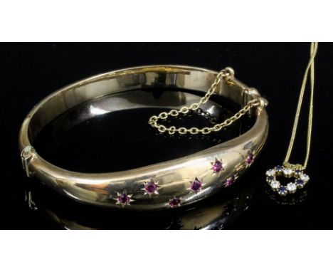 A modern 9ct gold stiff bangle in the "Victorian" manner, "Gypsy" set to the face with seven small rubies, internal measureme