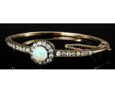 A late Victorian gold coloured metal opal and diamond set stiff bracelet, the cabochon cut opal of approximately 2.5ct, surro