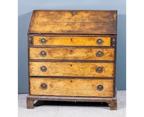 A late Georgian oak bureau, the slope enclosing pigeon holes and four small drawers, fitted four long graduated drawers under