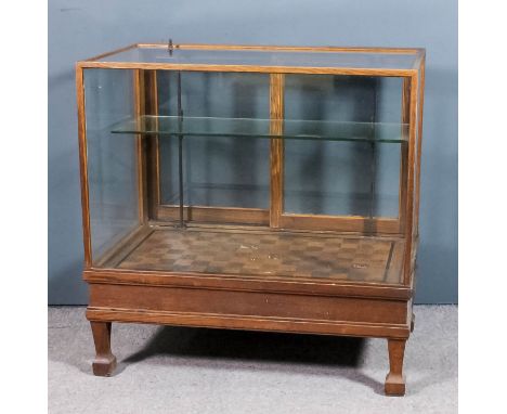 A 1930's oak framed and plate glass shop display counter, fitted one plate glass shelf enclosed by sliding glazed doors to re