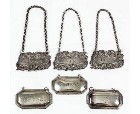 Three George IV silver wine labels die stamped with mask, lyre, urn, shell, floral, leaf and berry ornament and worded "Brand