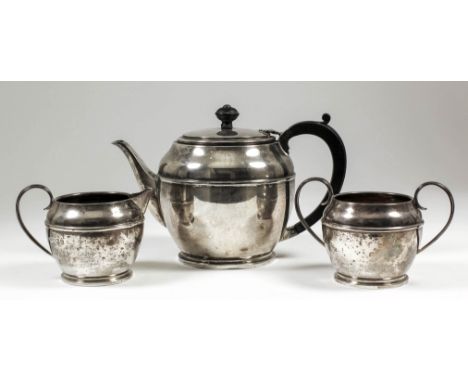 A George VI silver three piece tea service with plain circular bodies, moulded girdle and footrim, comprising - teapot, with 