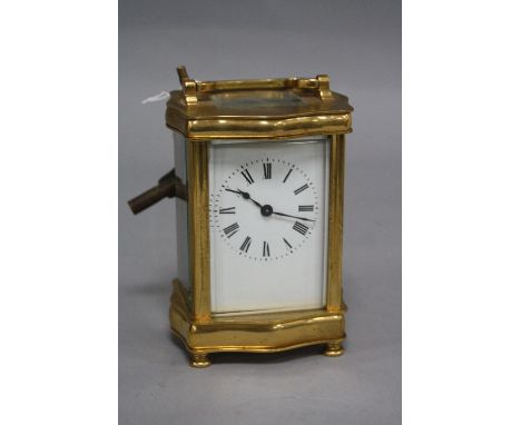 A 20TH CENTURY BRASS CASED CARRIAGE CLOCK OF SERPENTINE OUTLINE, enamel dial, Roman numerals, height 12.5cm to handle fitting